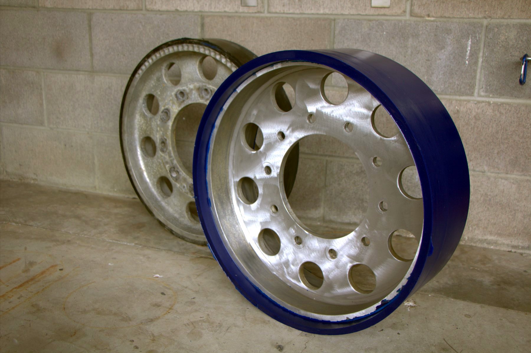 Worn bogie wheel next to a rebuilt urethane bogie wheel