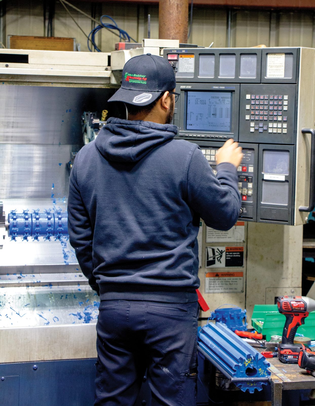 Blue urethane roller being finished on a lathe at the Urethane Specialists plant