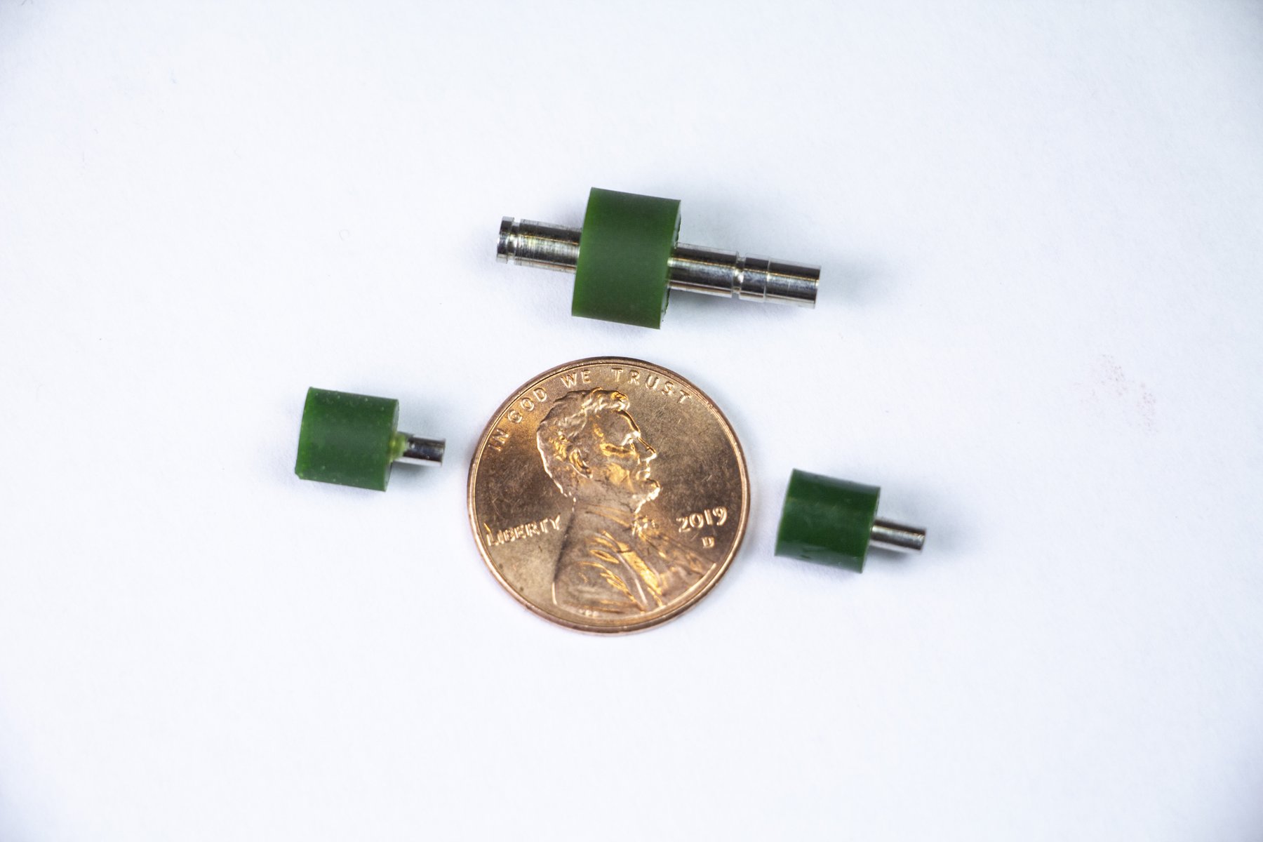 Miniature urethane rollers next to a penny for scale